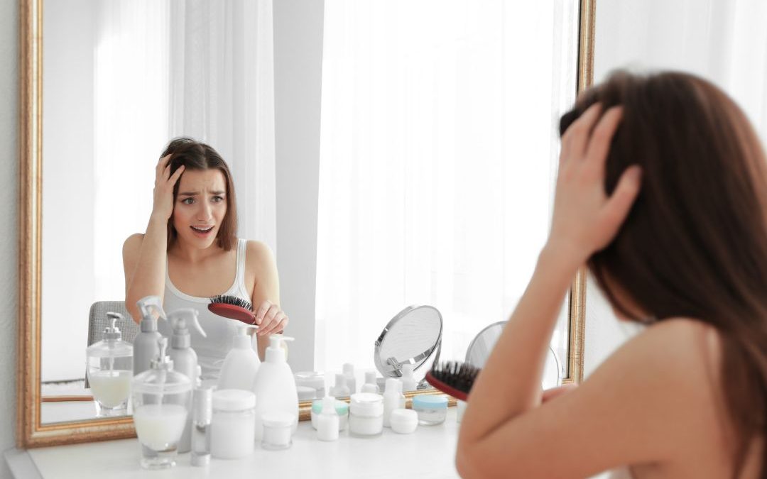 Mujer observando pérdida de densidad capilar frente al espejo